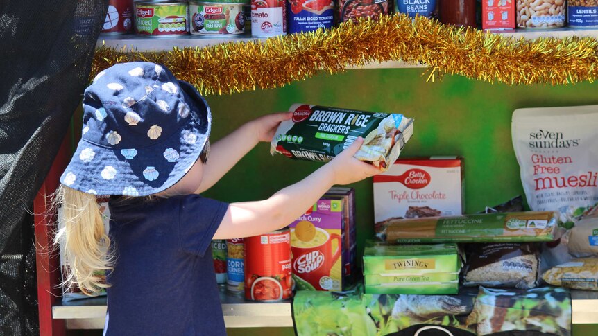 Girl puts crackers in the food pantry