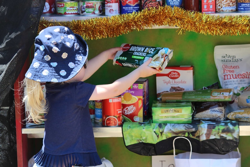 Girl puts crackers in the food pantry