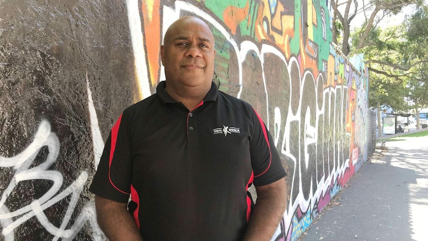 A man standing in front of colourful street art.