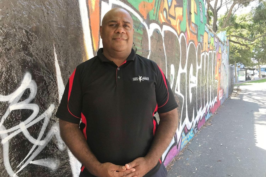 A man standing in front of colourful street art.