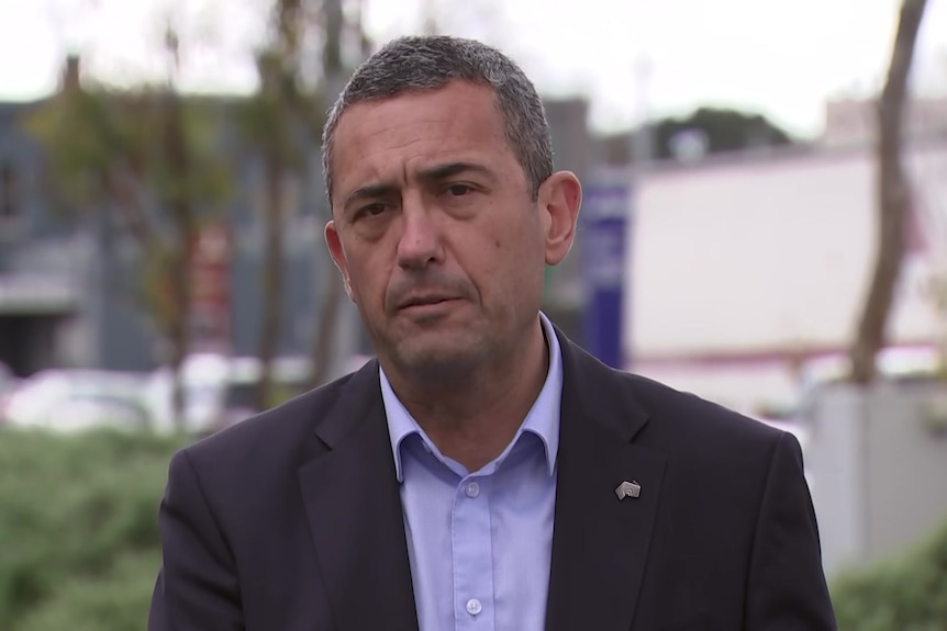 A man in a business suit speaking next to a busy road