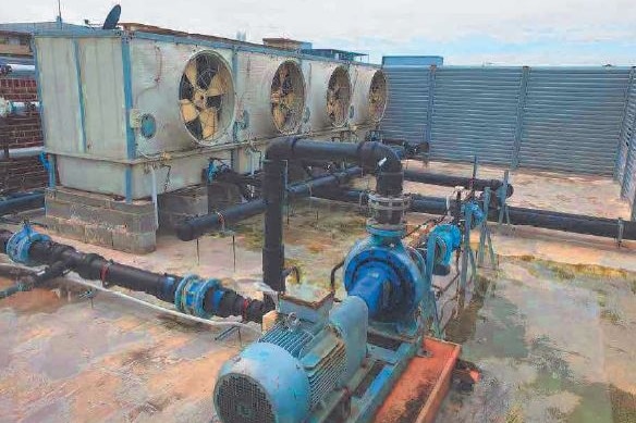 Water pools under an air-conditioning tower on an apartment building roof.