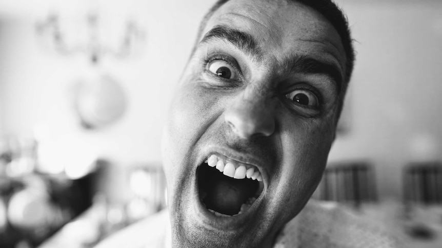 Black and white photo of close up of man's face with his mouth wide open.