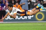 Close-up of a Brisbane Broncos winger flies through the air as he dives to score a try during an NRL game.
