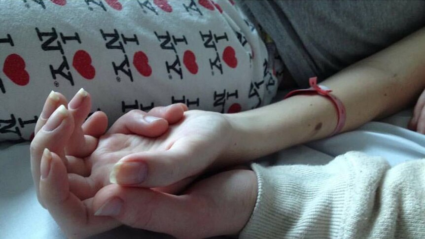 Cassie's cousin holding her hand just days before she died.