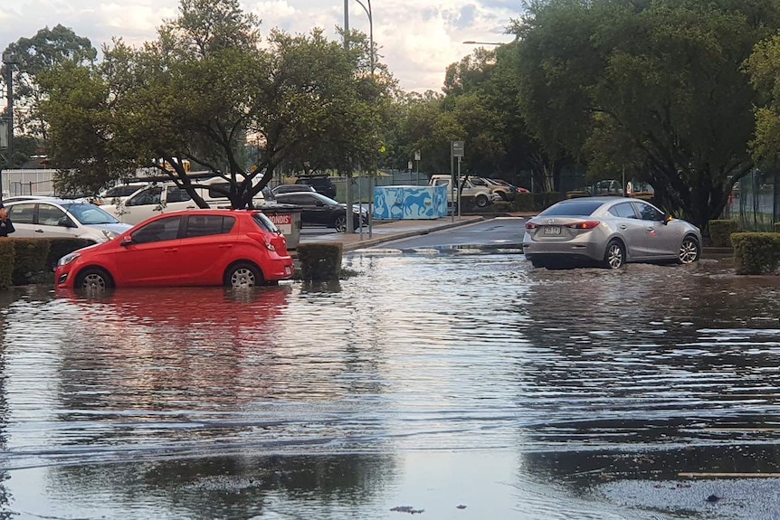 Cars drive through water in the car park of Wacol train station in Brisbane's south-west after storms on March 2, 2021