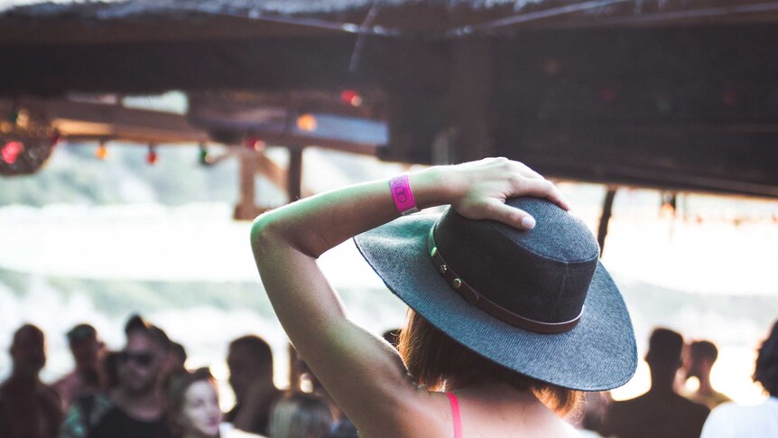 Shot of young woman from behind at a festival wearing a hat