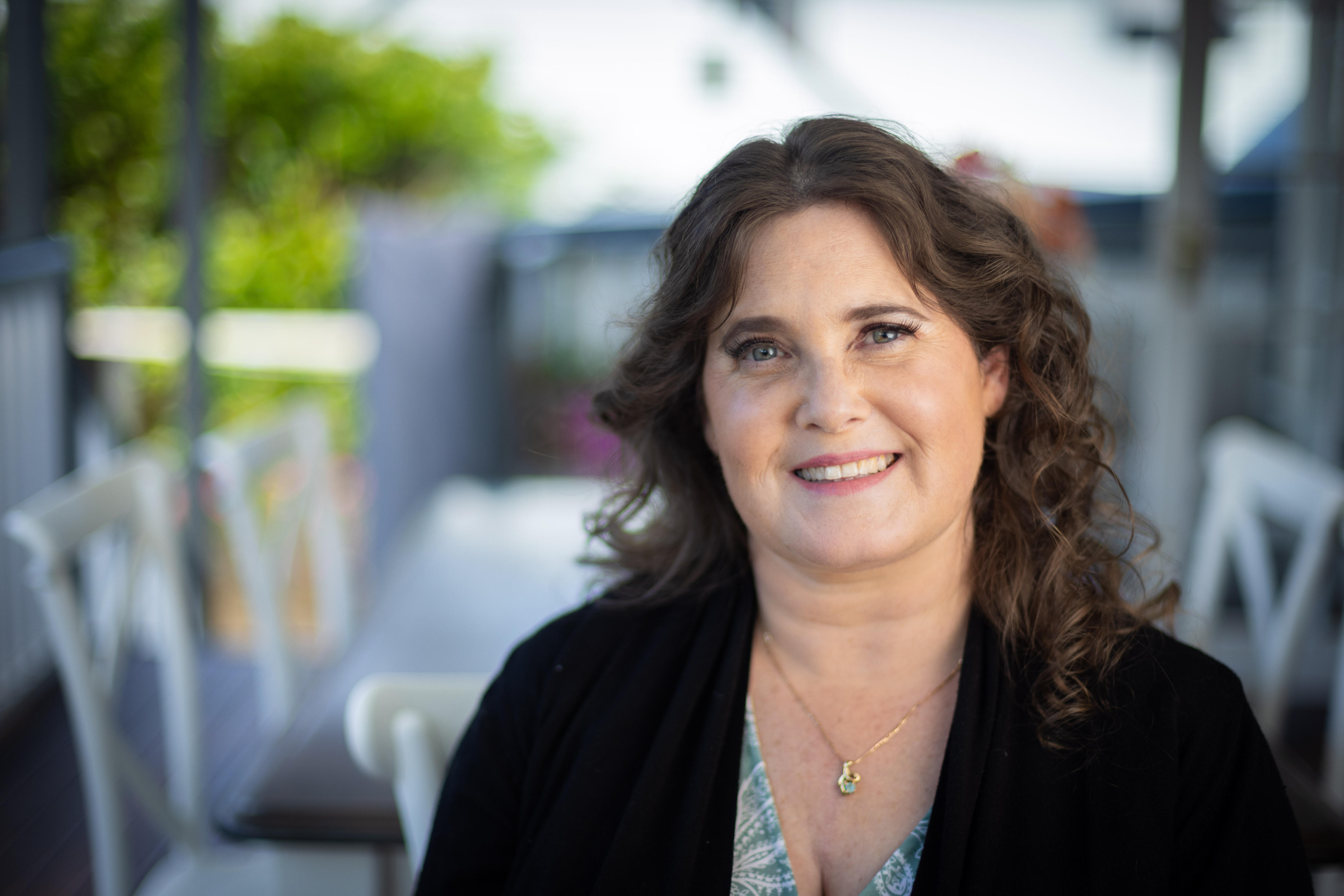 A woman in a black shirt smiling at the camera
