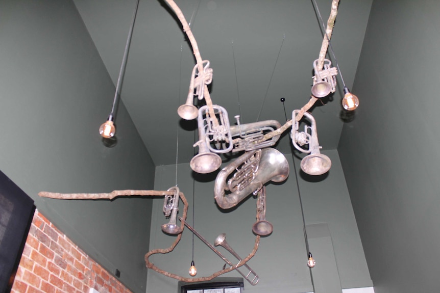Old Salvation Army brass instruments suspended from timber branch on ceiling of former Citadel now entertainment precinct