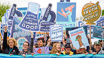 People passionate about science rally holding signs saying 'protect science' and similar.