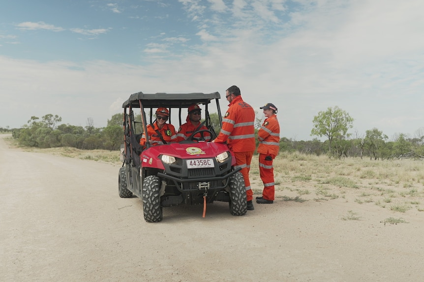 Four SES members in hi-vis standing around a four-wheeler.