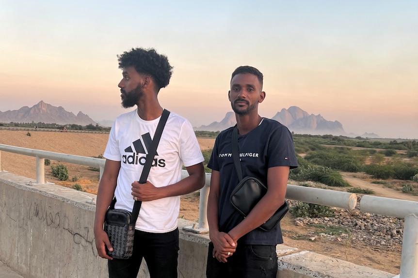 Two man standing in front of a desert landscape