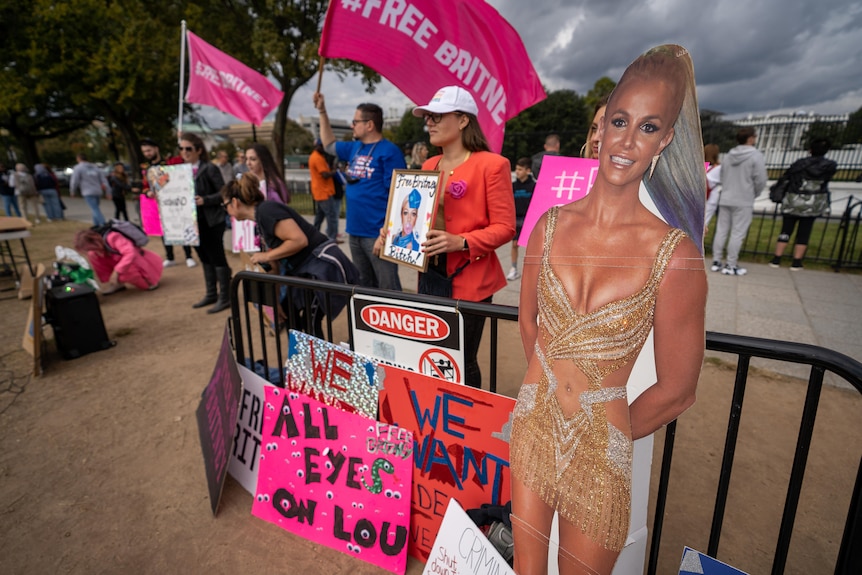A protest with people holding 'Free Britney' signs among cardboard cut-outs of Britney Spears