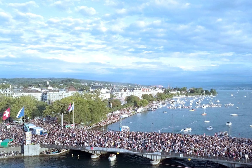 Crowds of people gather over a bridge in Switzerland.
