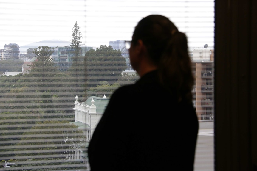 A woman looks out a large window