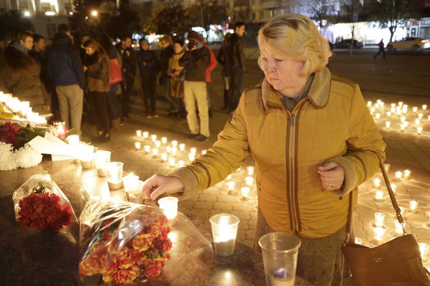 A woman lights a candle in honour of victims of a Russian airliner crash
