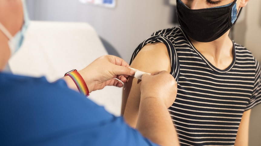 Doctor places bandage on patient's arm where vaccine was injected.