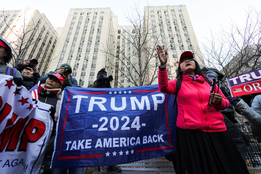 A group of protesters hold signs saying Trump 2024 Take America Back