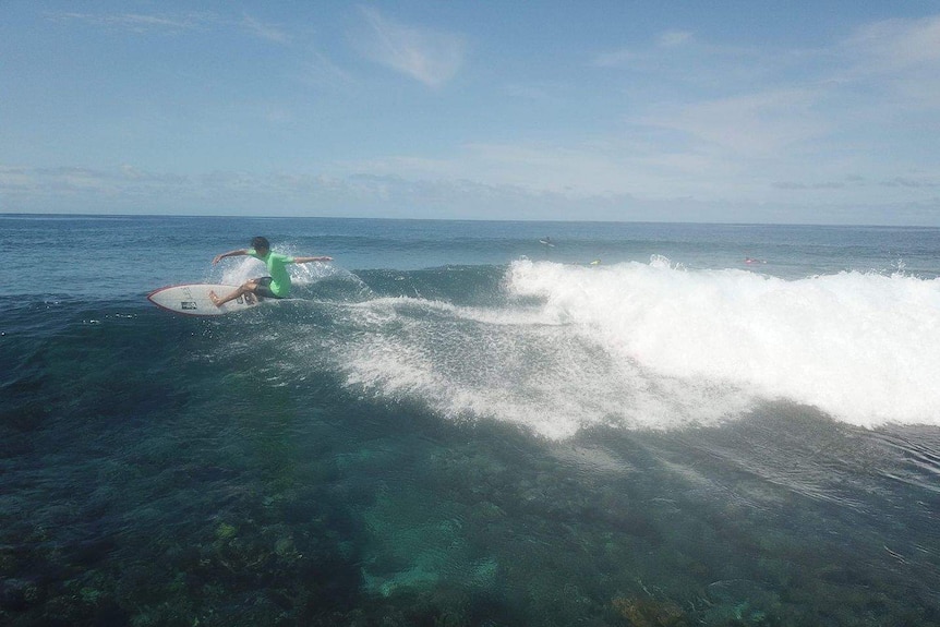 Wide shot of a surfer catching a wave.