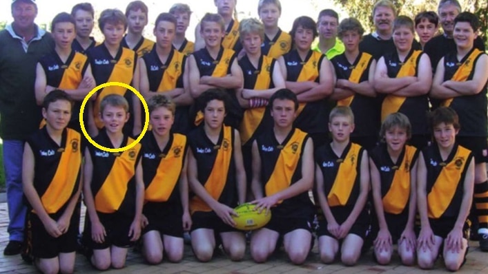 A team of young football players standing wearing yellow and black jumpers