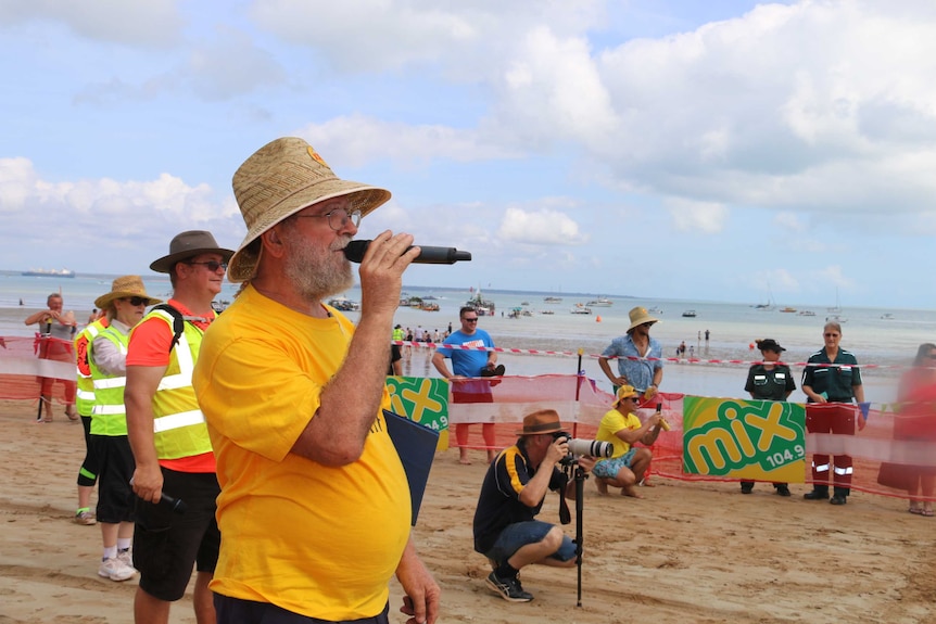 Des Gelert speaks into a microphone at Mindil Beach for Darwin's Beer Can Regatta.