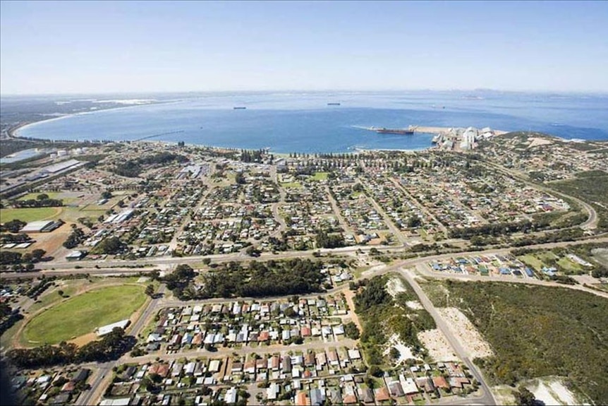 An aerial view of a town with a wide, sweeping bay and a port with ships.