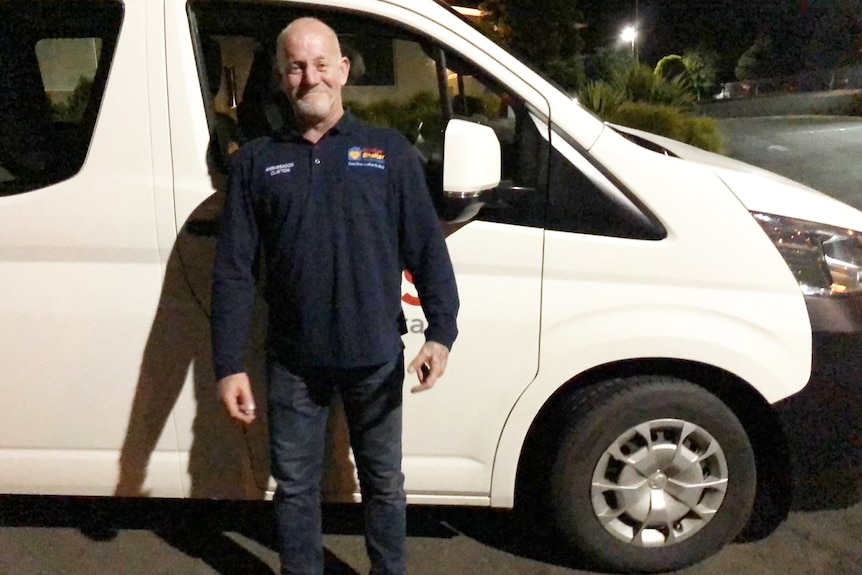 man in dark clothes standing in front of mini bus door 