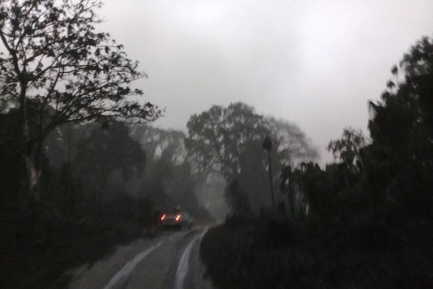 A car drives down a street covered in ash