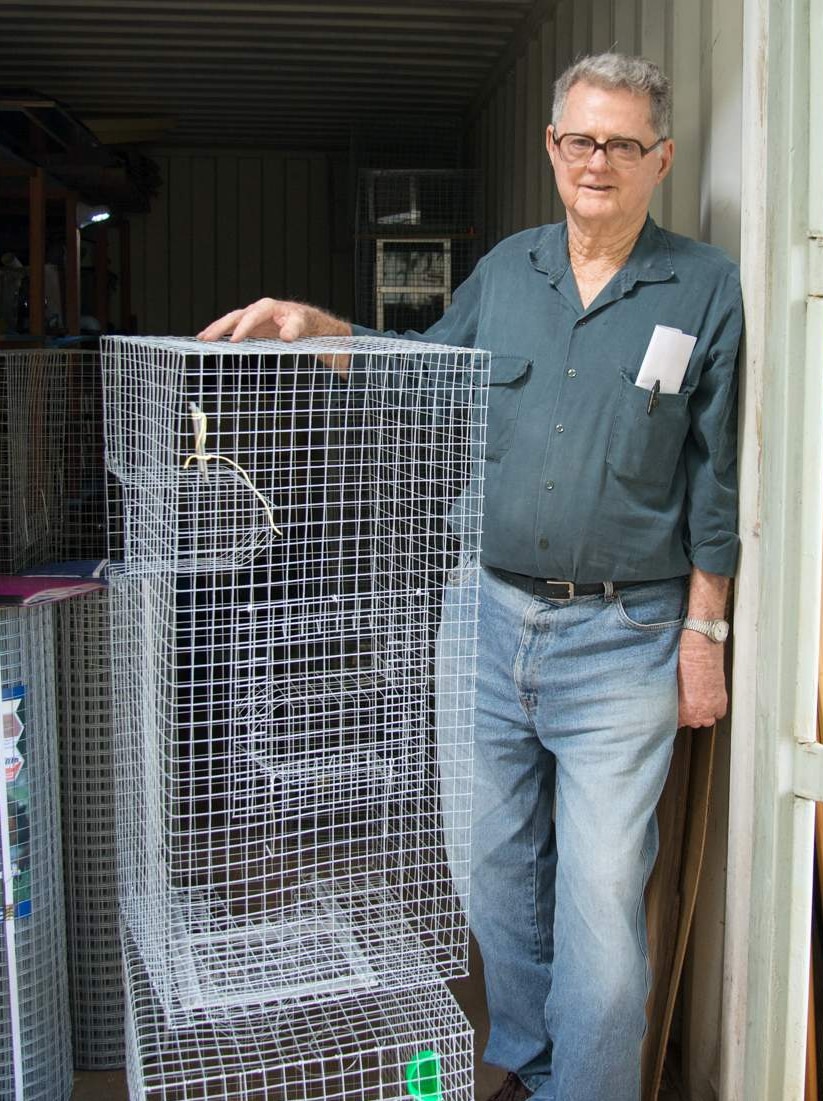 Ron Moon stands at the entrance of a shipping container filled with traps built at the Cairns Men's Shed.