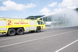 An aviation rescue fire truck sprays water from the monitor (turret) fixed to the roof of the driver's cabin.