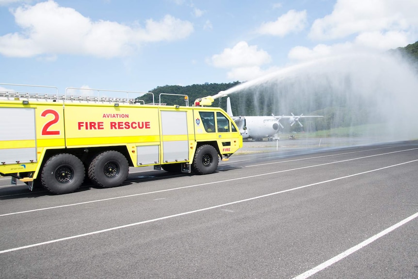 An aviation rescue fire truck sprays water from the monitor (turret) fixed to the roof of the truck's cabin.