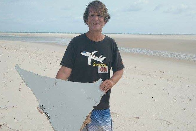 Blaine Gibson holds part of a wing on a beach.