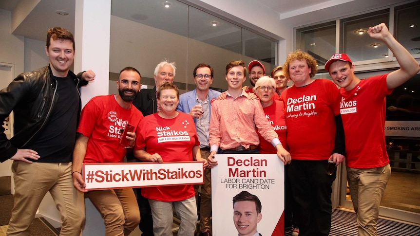 Declan stands amongst supporters, holding signs.