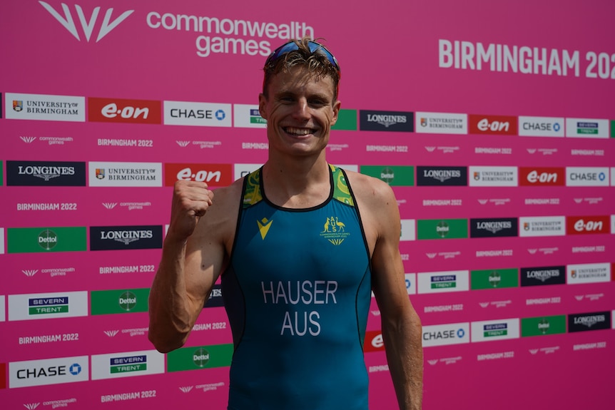 A male athlete wearing green pumps his fist in celebration