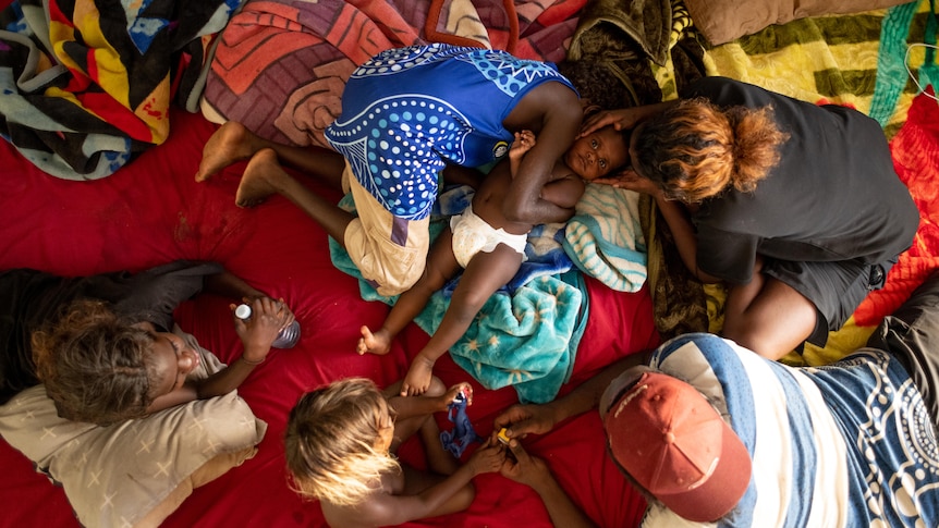 Children play on a bed in the lounge room during the heat of the Rockhole day.