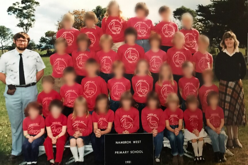 An old school photo with a male and female teacher. The faces of children are blurred. 