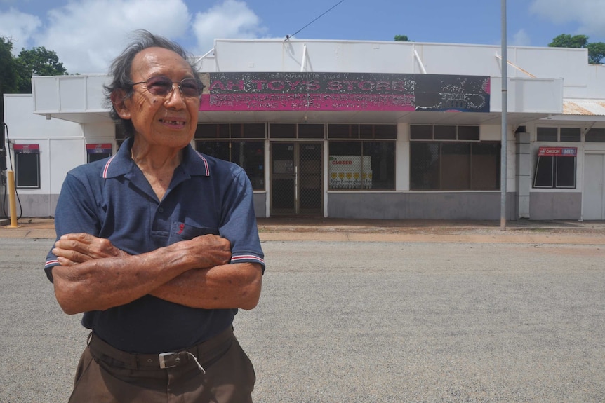 Eddie Ah Toy stands in front of his closed store with arms folded.