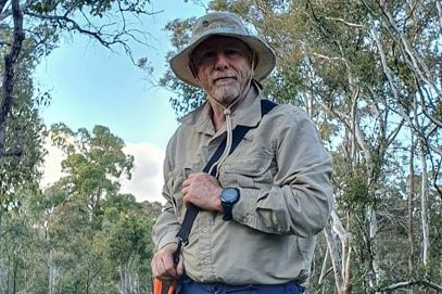 A man in Khaki shirt and had stands in the bush