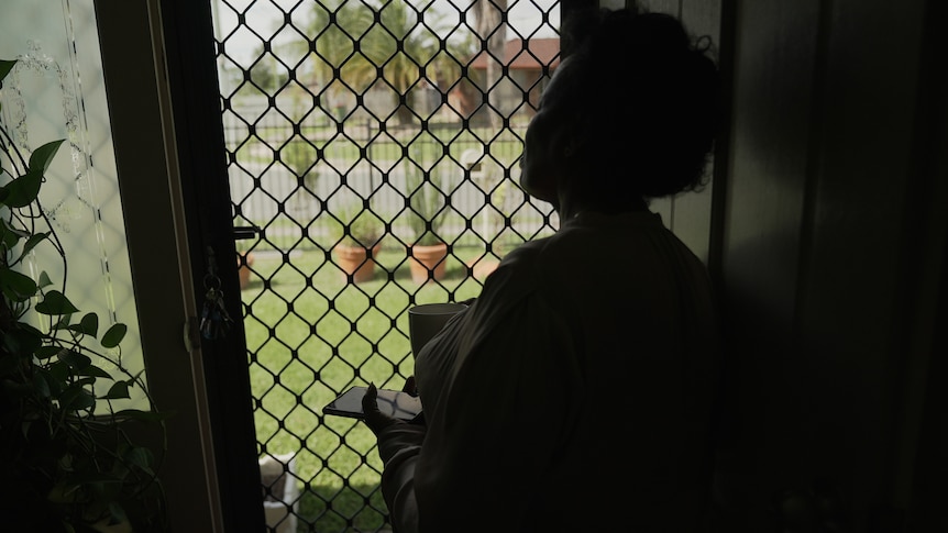 a woman holding a phone looking out the door