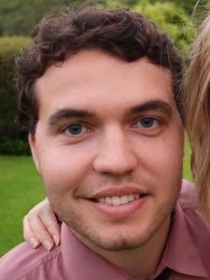 A smiling man wearing a tie looks at the camera.