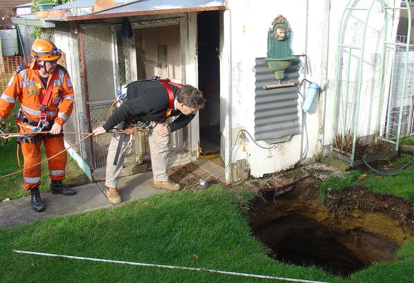 ses workers lower themselves into a sinkhole
