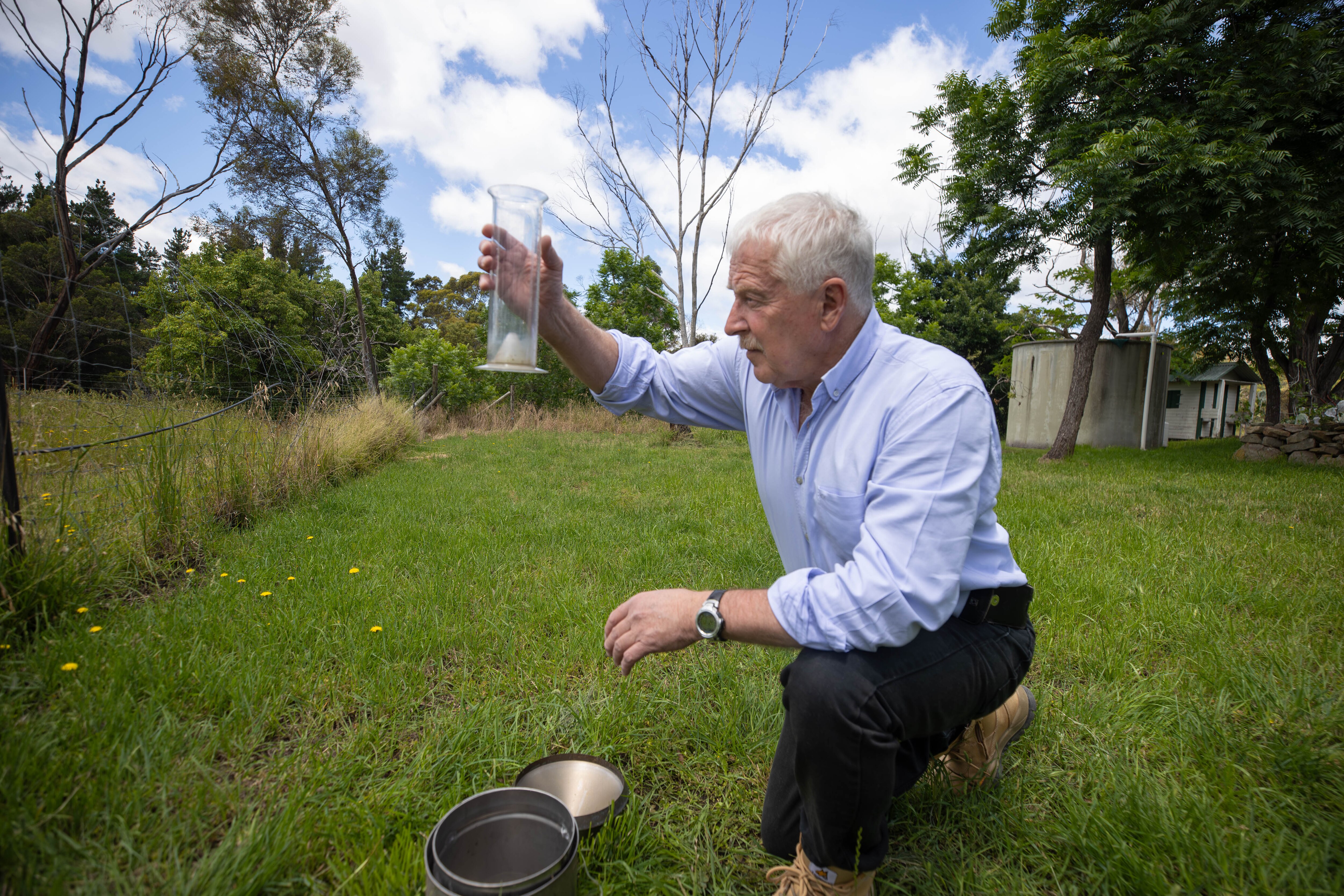 Зәңгәр күлмәк кигән кеше яңгыр үлчәвен тикшерә.