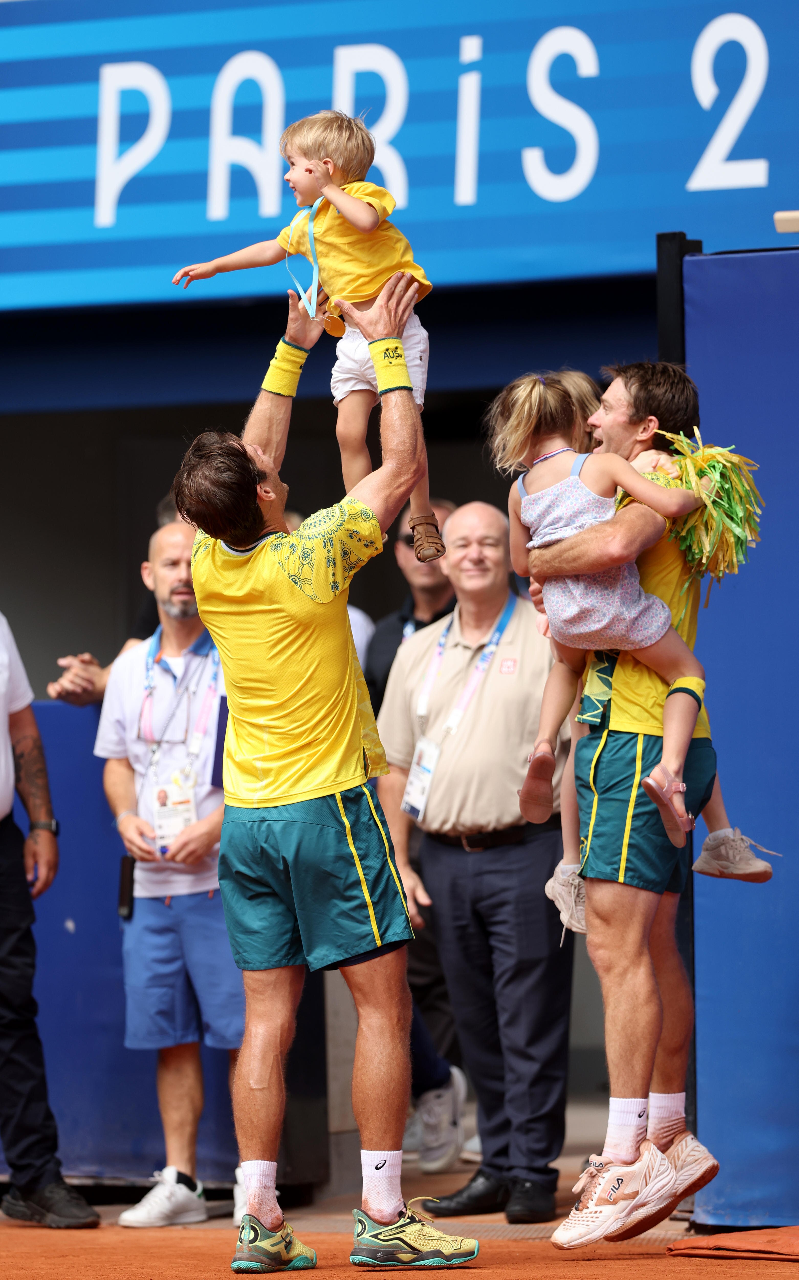 Matt Ebden gently throws his young son into the air, who is wearing a homemade gold medal