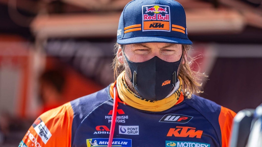 Toby Price wears a face mask and  blue cap with his full riding kit
