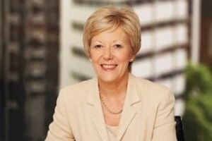 Sandra Birkensleigh sitting at a desk smiling with pen in her hand.