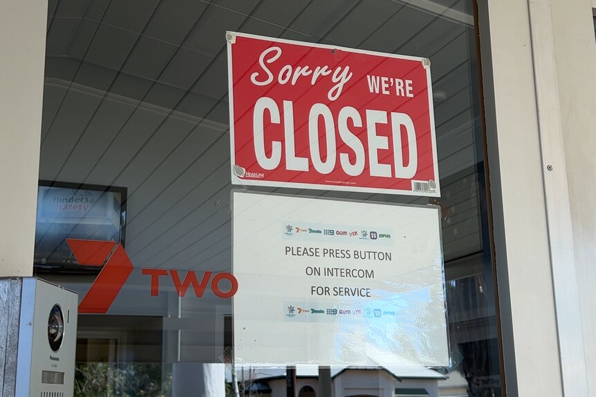 A sign that says "Closed" hanging in a glass door featuring Seven Network branding.