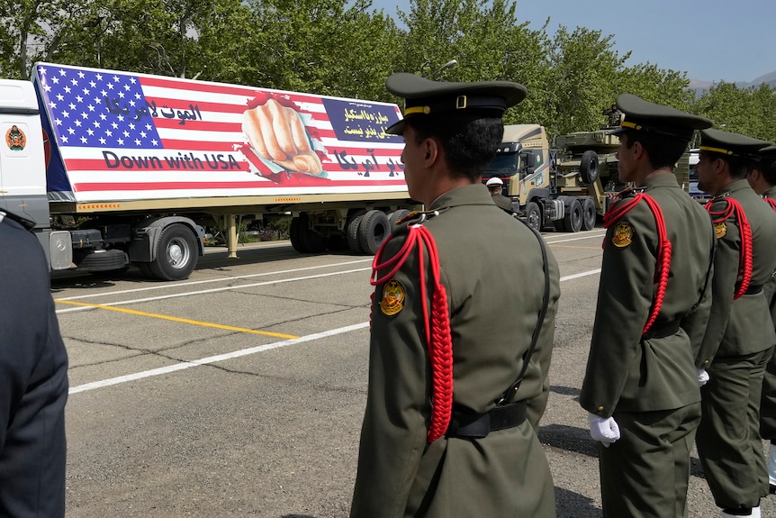 A truck parades a banner of the American flag with the words 'down with USA' printed on it