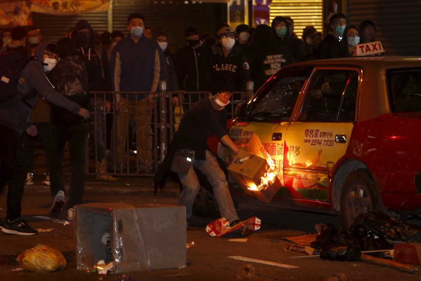 A protestor sets fire to a taxi during night time protests at Mongkok distrcit in Hong Kong