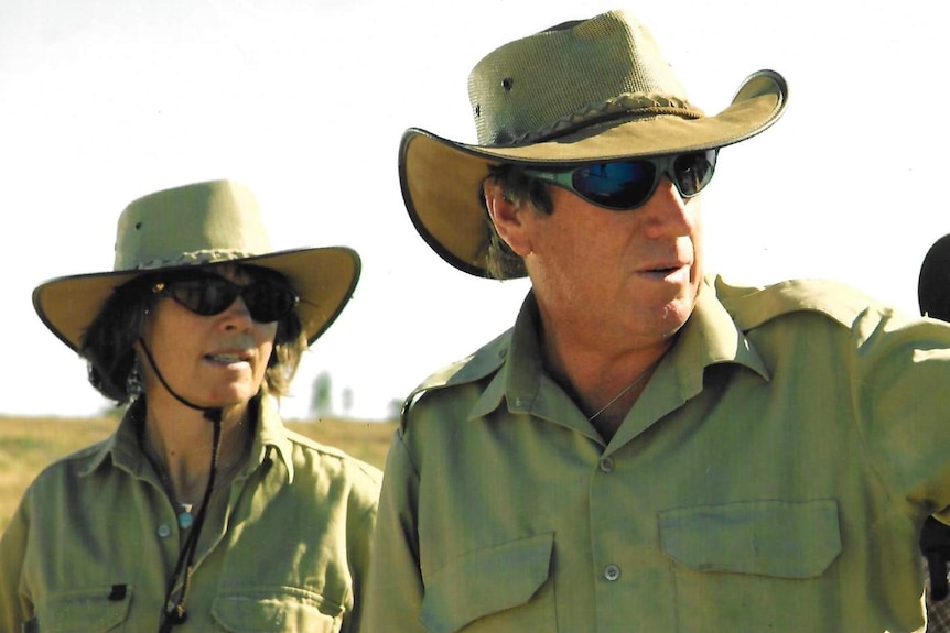 Two people wear light green cloths and cowboy hats.