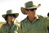 Two people wear light green cloths and cowboy hats.